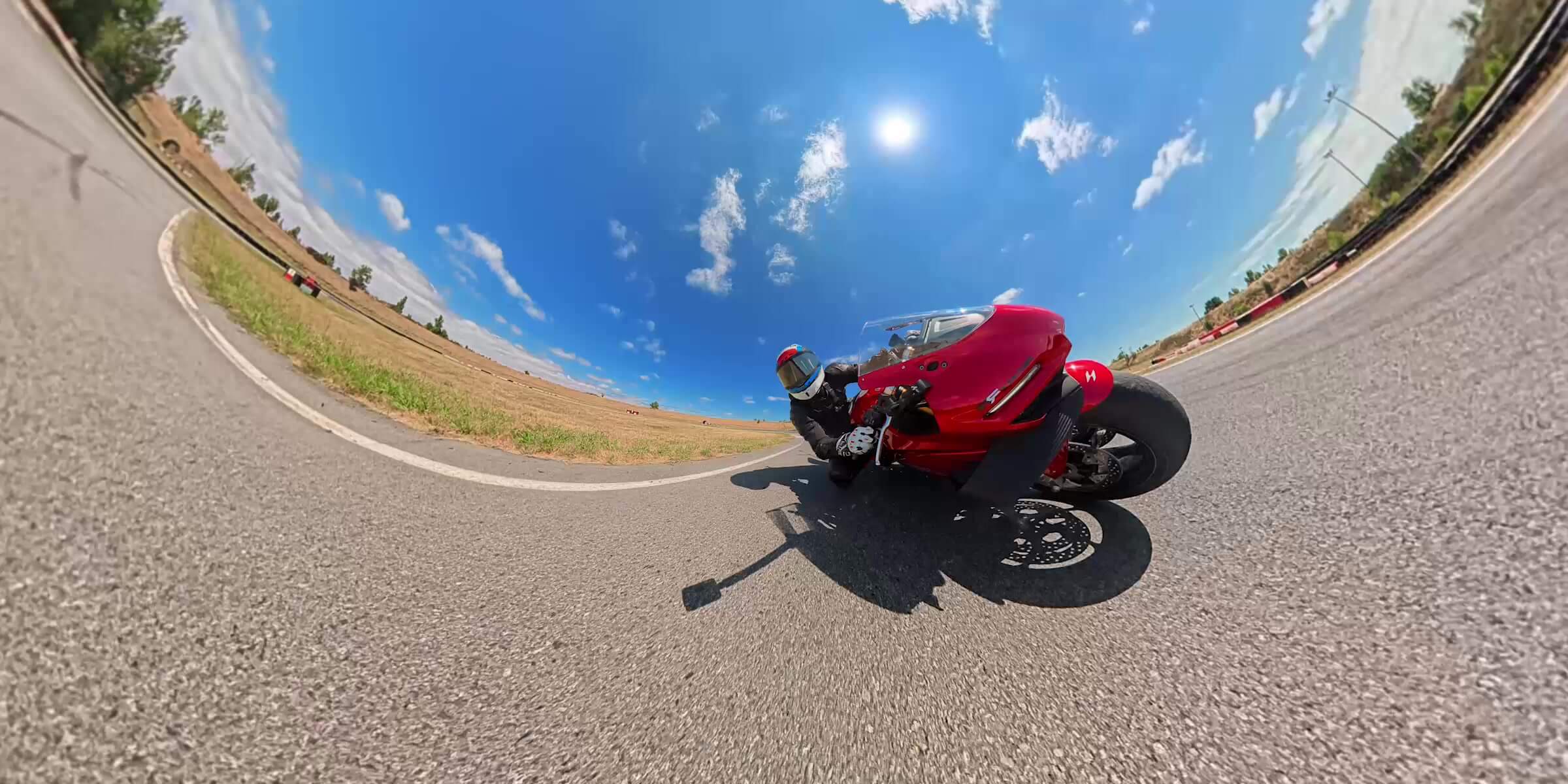 Red sport motorcycle leaning through a corner in a wide 360 camera frame