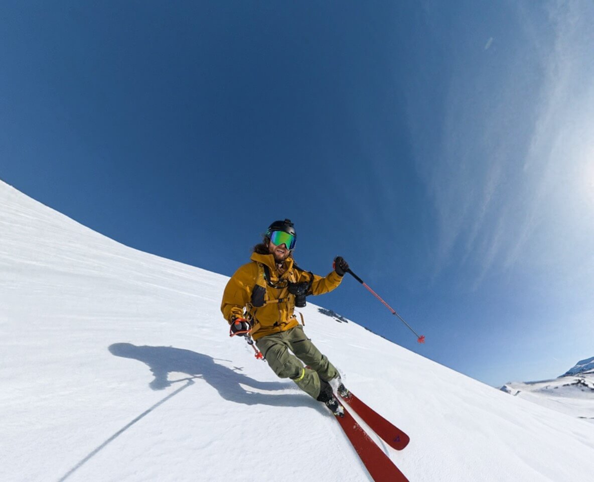 Skier in a yellow jacket recording with DJI Osmo 360 II in a snowy alpine landscape