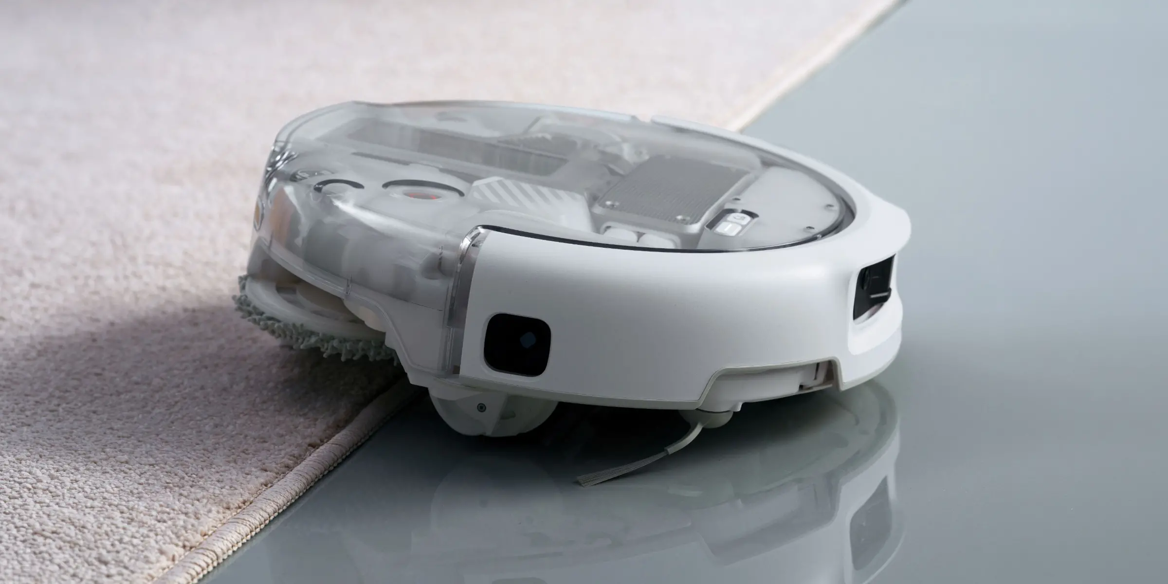 DJI ROMO P2 z transparentną stacją w jasnym salonie, obok czytającego domownika