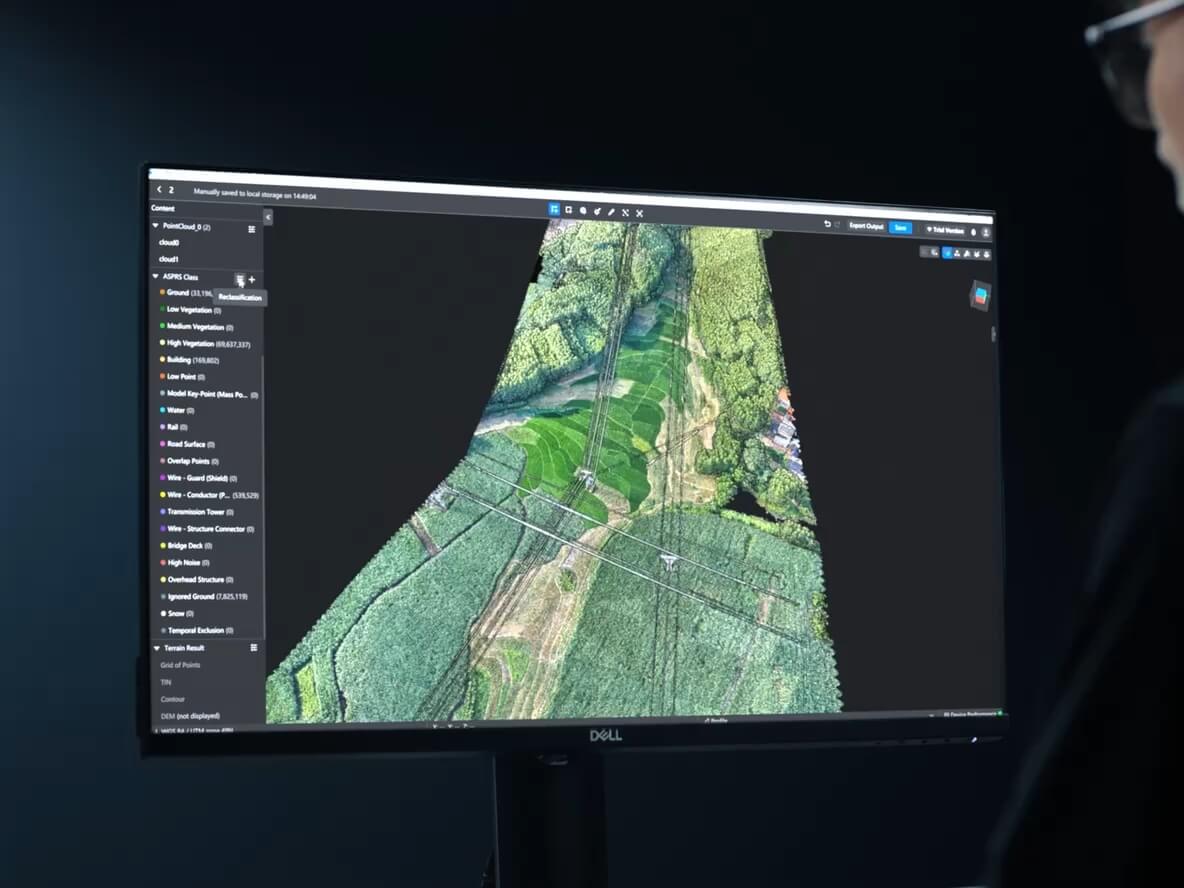 Monitor displaying a coloured power-corridor point cloud in DJI promotional photography