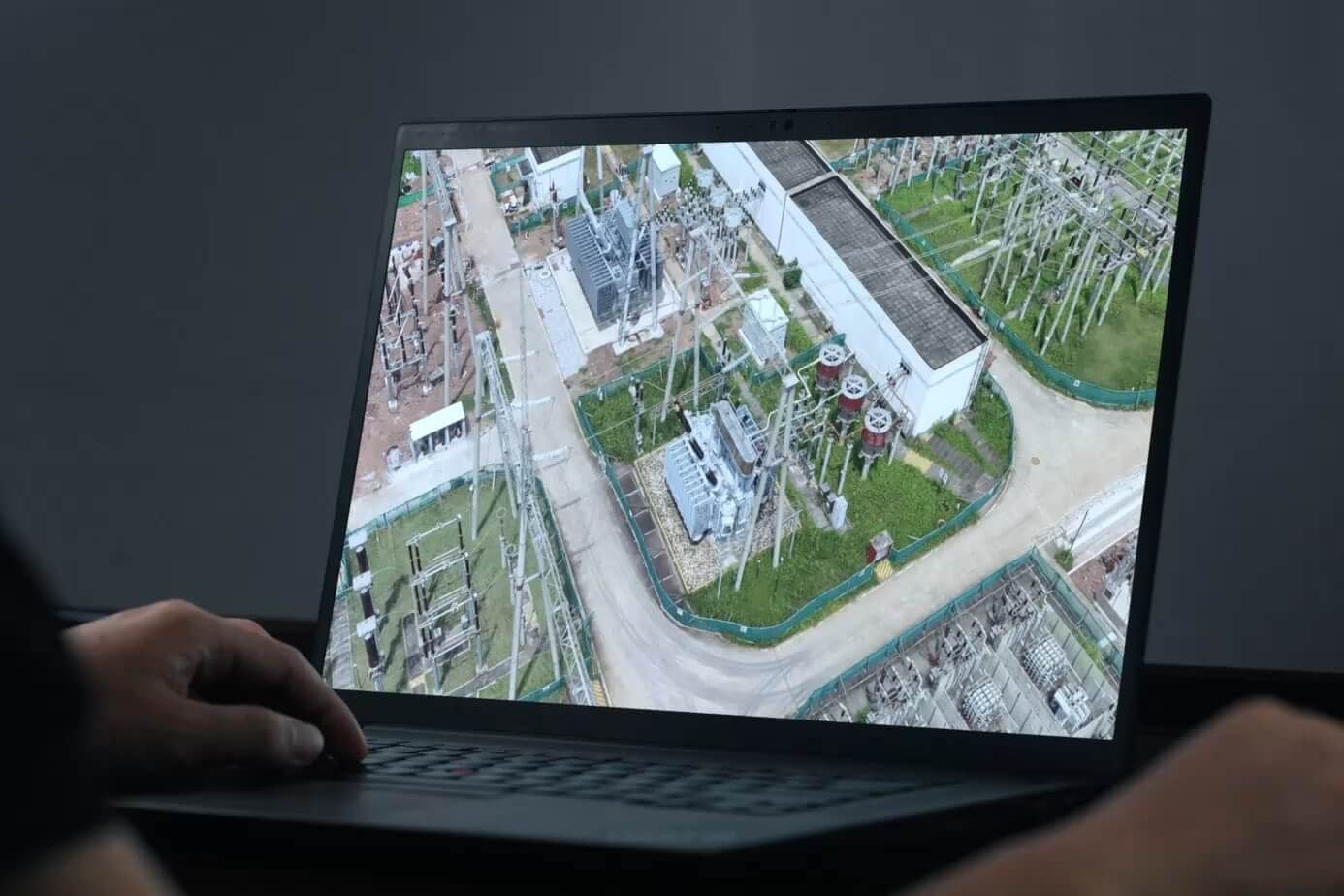 Laptop displaying a digital model of dense electrical substation infrastructure in DJI promotional photography